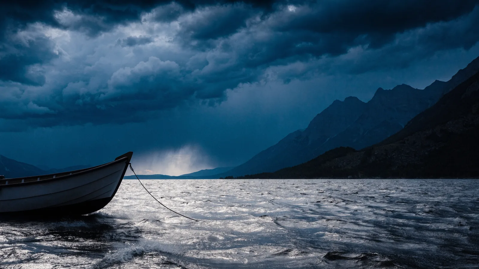Gewitterwolken über einem Alpensee mit vertäutem Boot