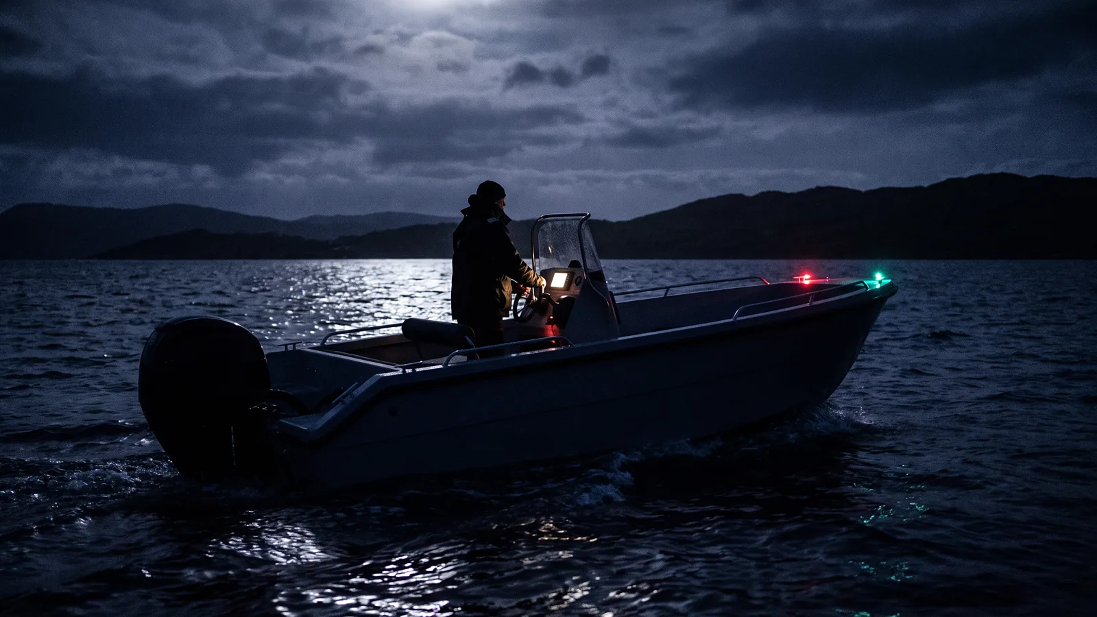 Motorboot nachts in Fahrt, Positionslichter über dem Wasser