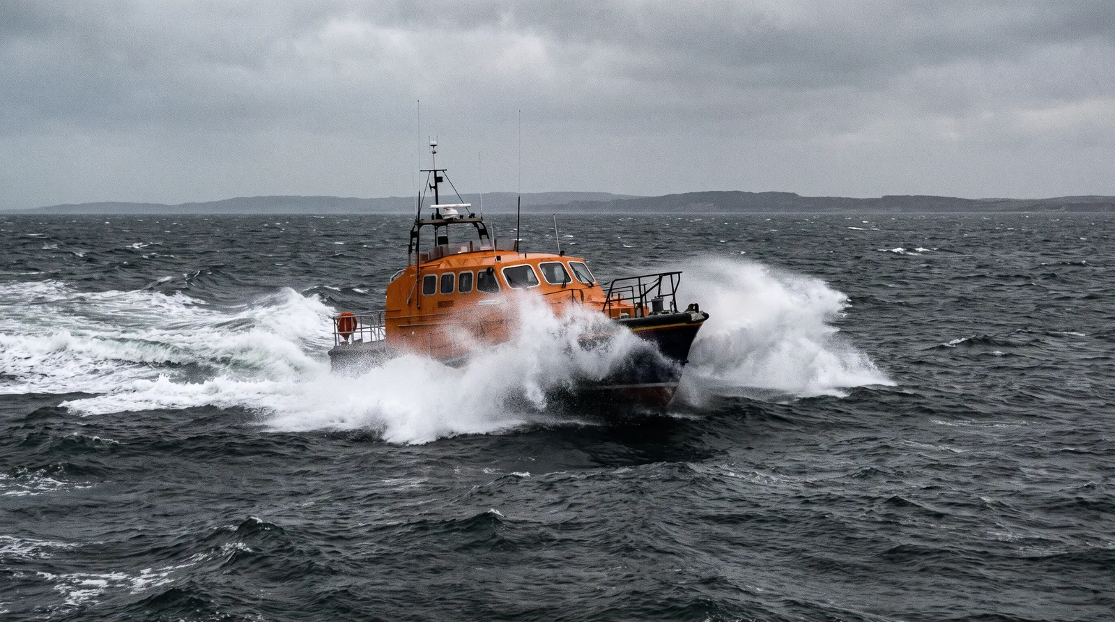 An all-weather lifeboat seen from astern punching through a steep grey sea