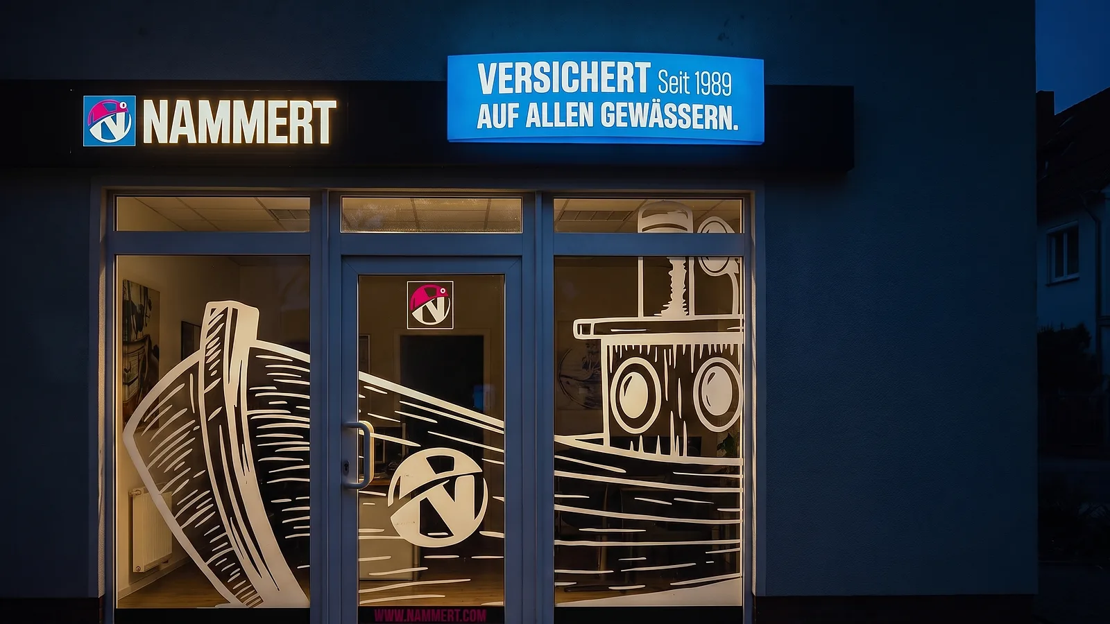Das Büro der NAMMERT Assekuradeur GmbH in Königs Wusterhausen am Abend, Schaufenster mit beleuchteten Schildern
