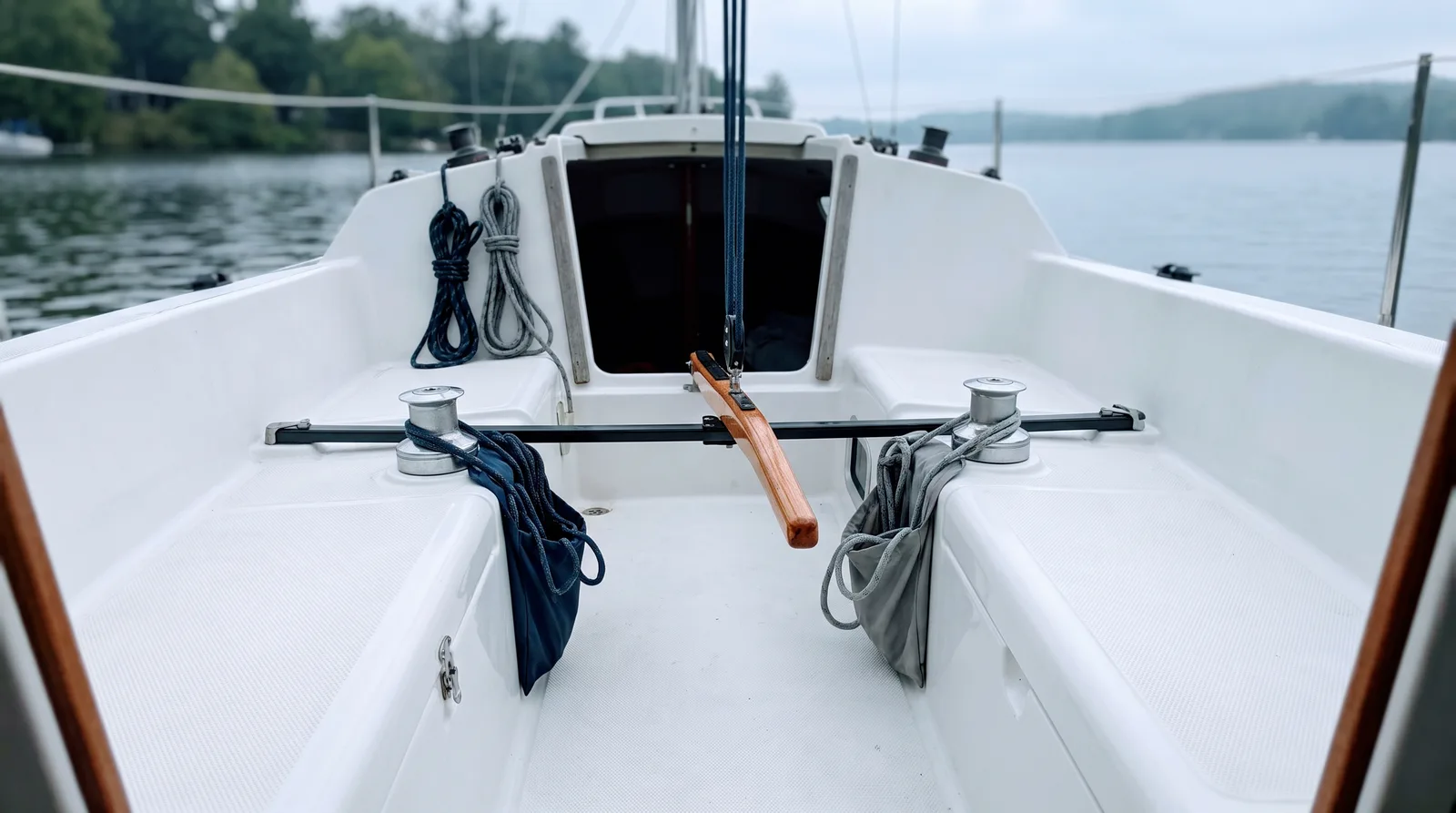 Cockpit eines kleinen Segelboots mit Pinne, Winschen und aufgeschossenen Leinen.