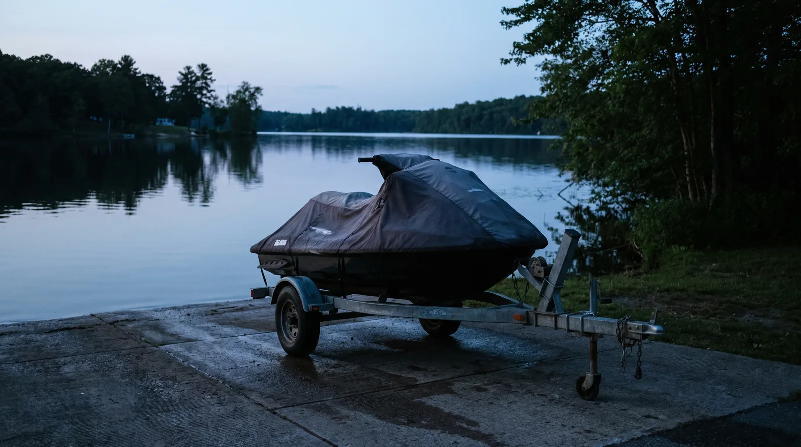 A jet ski on a trailer at a concrete slipway on a lake at blue hour.