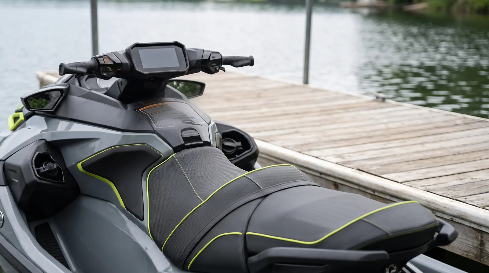 Lenker mit Anzeige vor der langen schwarzen Sitzbank mit grünen Nähten eines modernen Jetskis am Holzsteg.