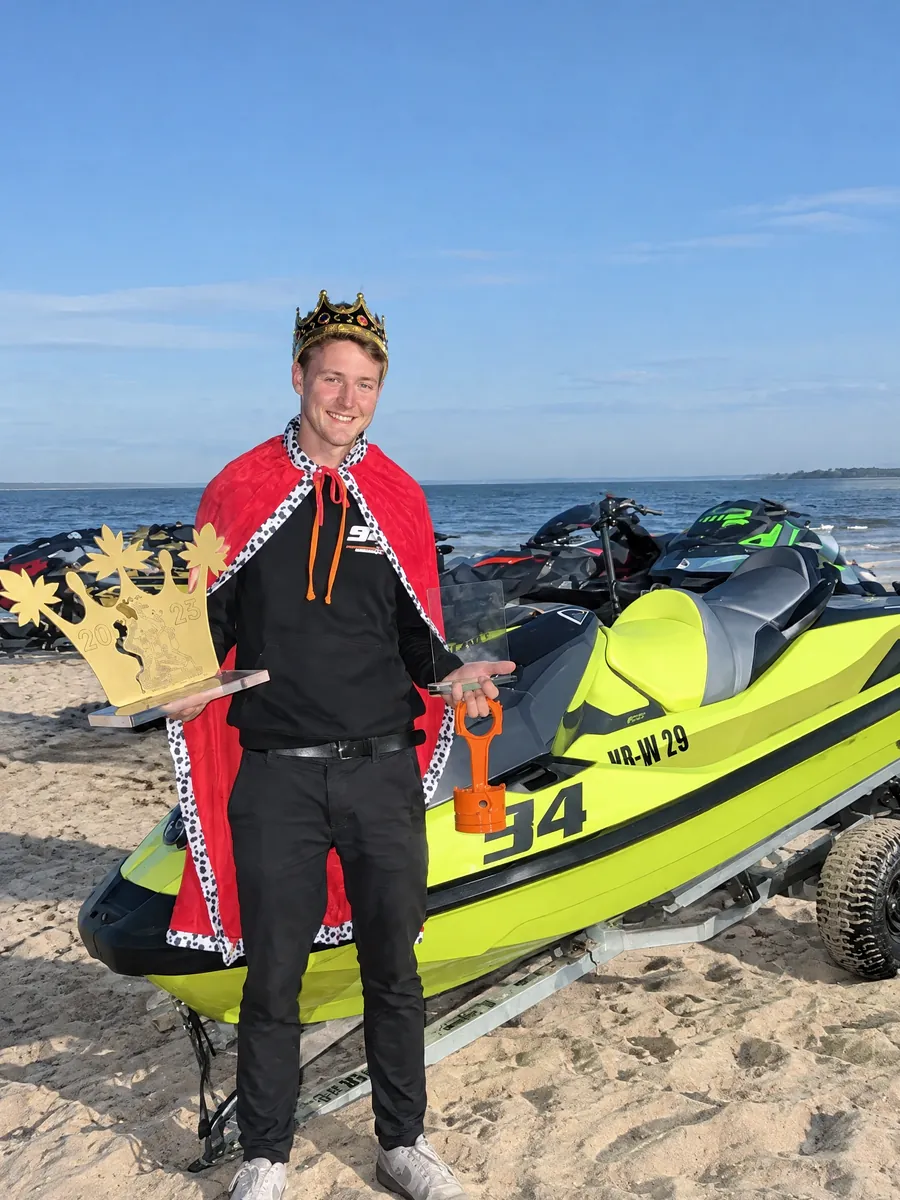 Justin P. mit Krone, Königsmantel und Pokal als King of Beach 2025 am Strand, neben seinem Jetski mit Startnummer 94 und NAMMERT Logo am Rumpf