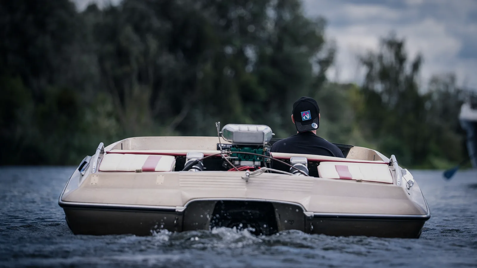 Sportboot in Fahrt von achtern, offen liegender Motor und Antrieb dicht über dem Wasser