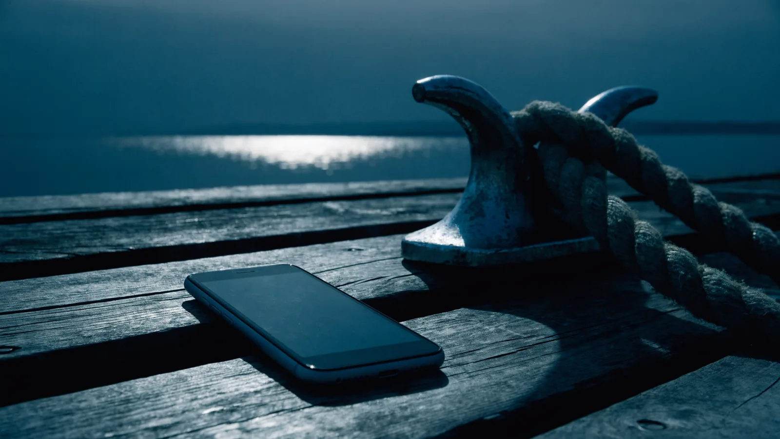 Smartphone auf den Planken eines Stegs neben einer Klampe