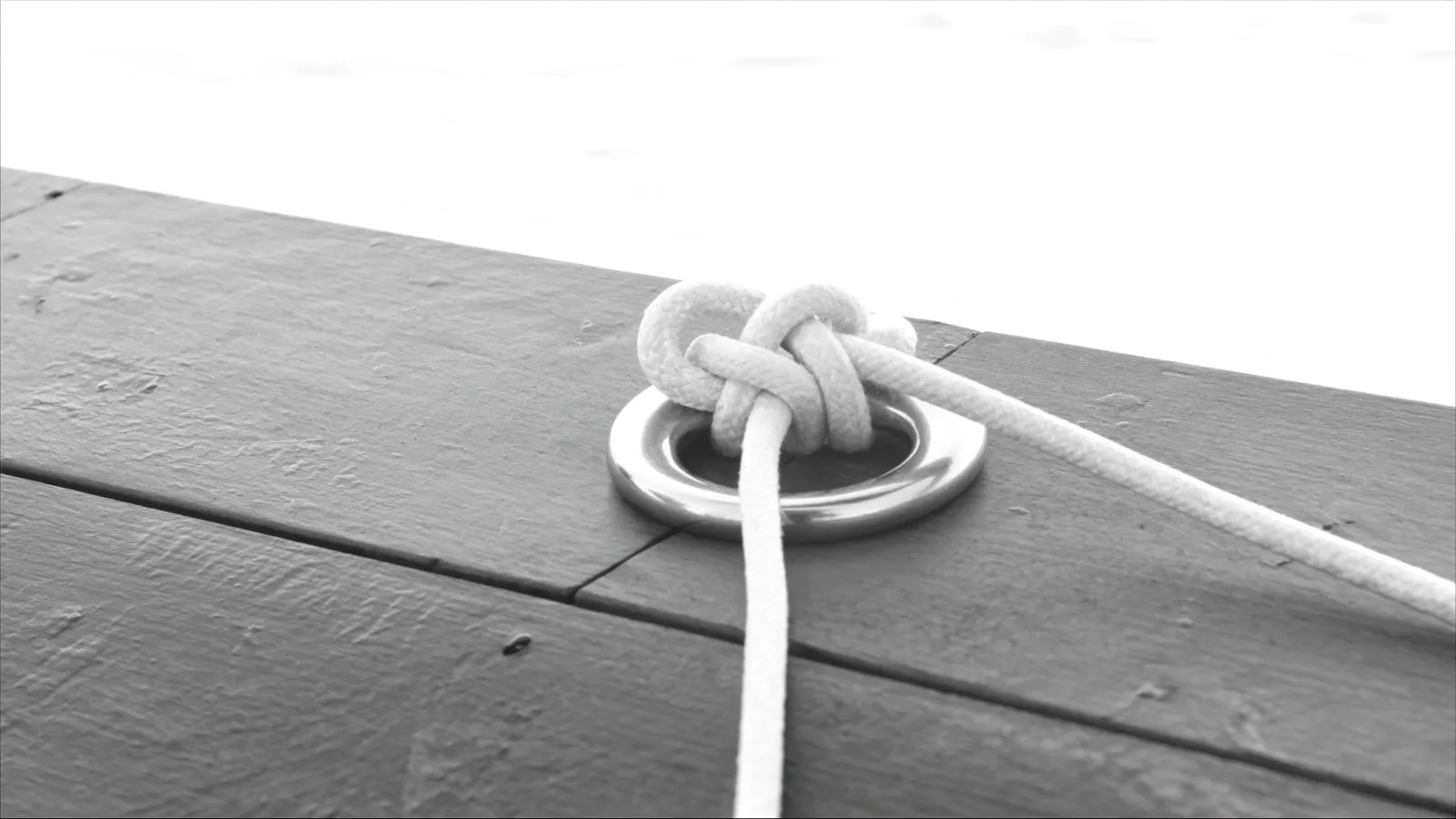 Knoten in einer Festmacherleine an einem Ring im Steg
