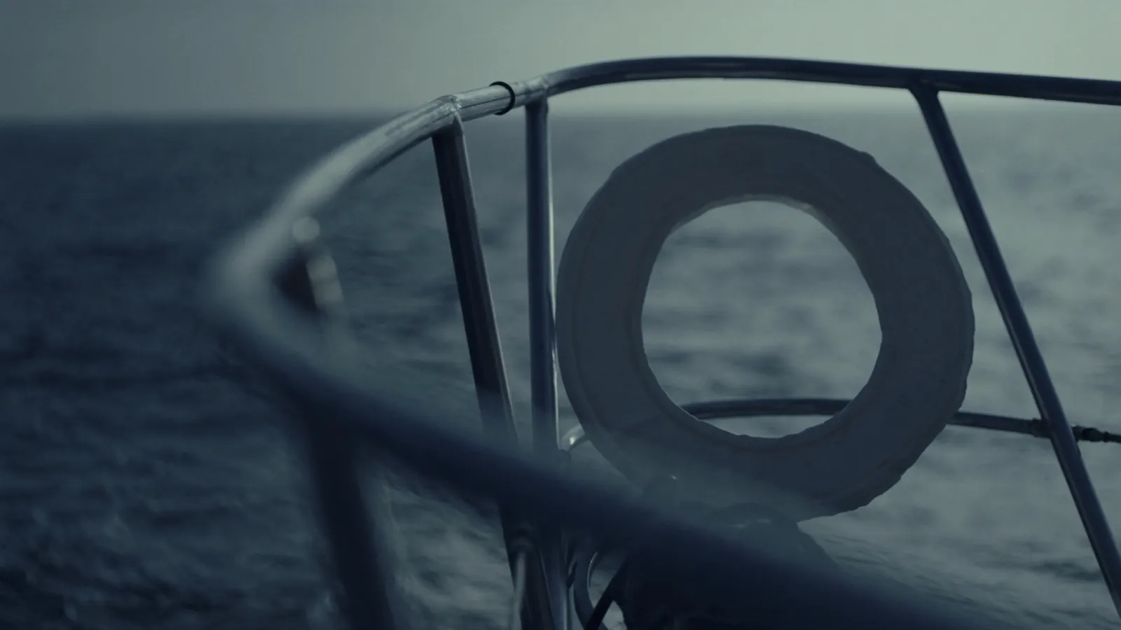 A lifebuoy on the pushpit of a sailing yacht, grey sea behind