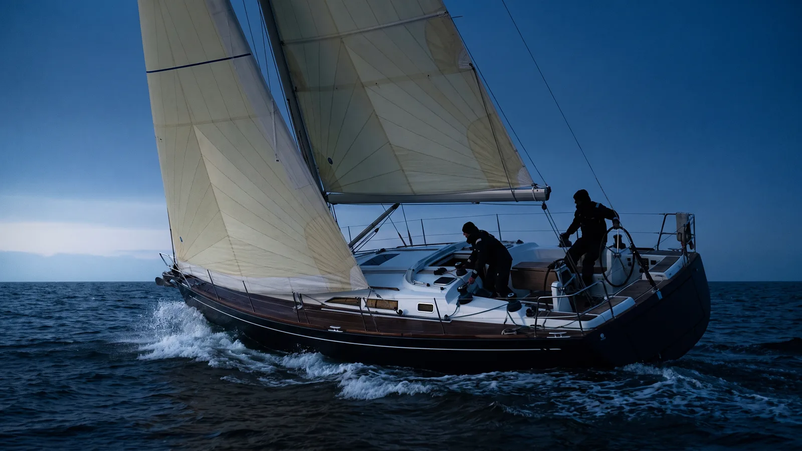 Segelyacht unter vollen Segeln zur blauen Stunde