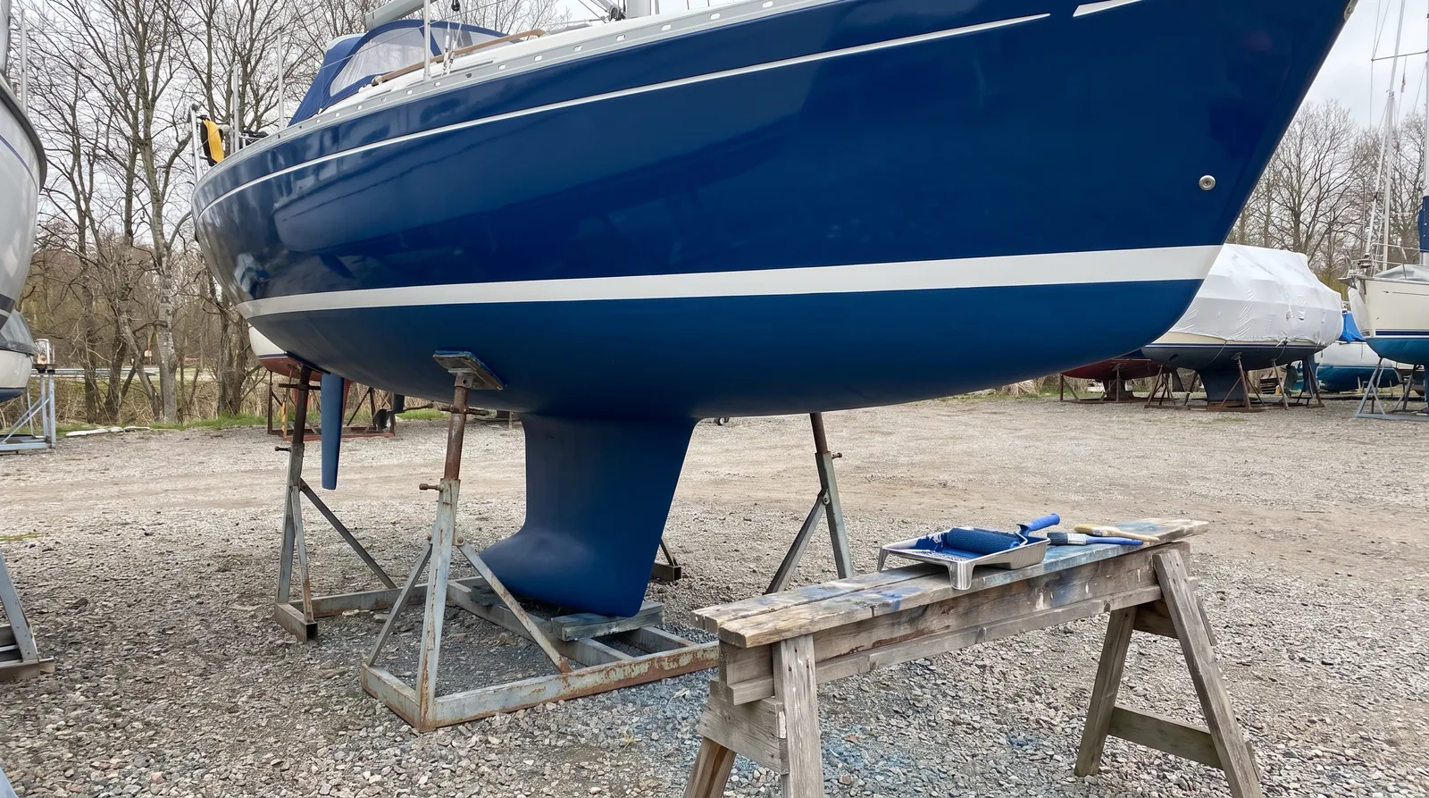 Frisch gestrichenes dunkelblaues Antifouling am Unterwasserschiff einer Segelyacht im Winterlager