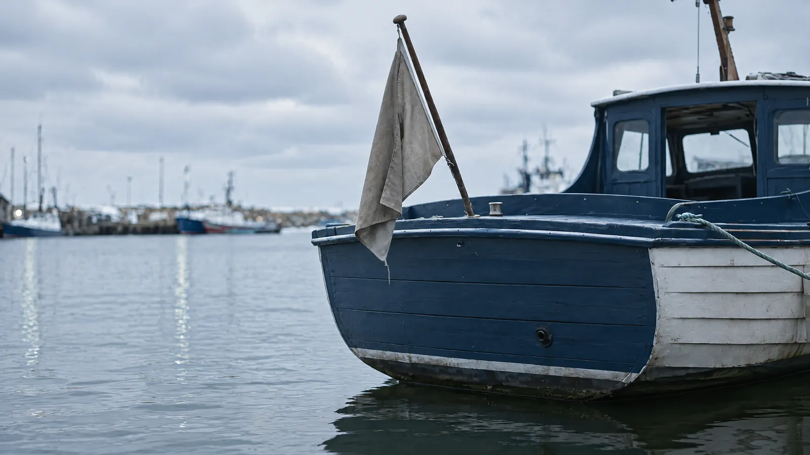 A small ensign hanging on a boat stern in daylight above the bare transom