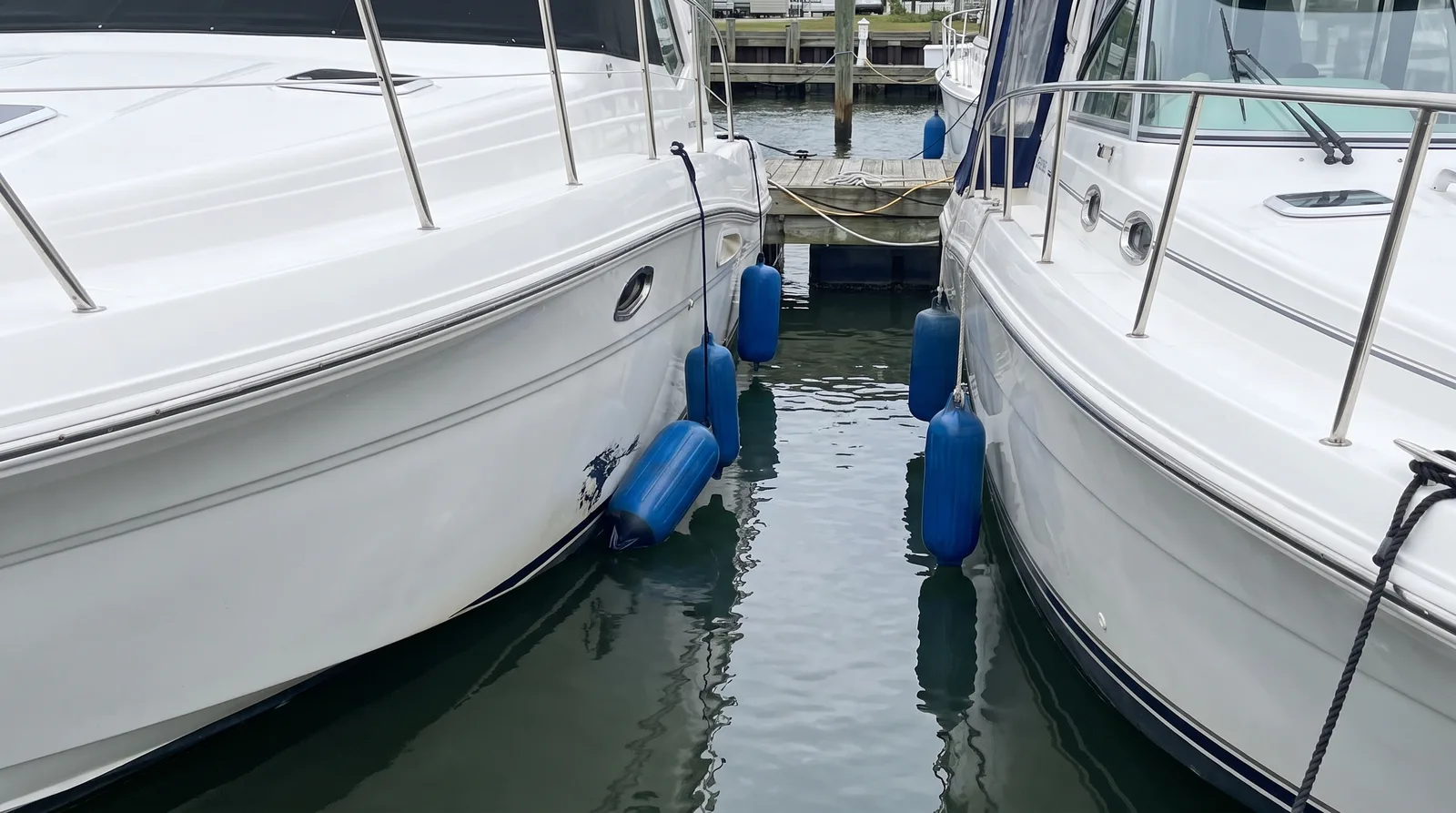Zwei Motoryachten dicht nebeneinander im Hafen mit Fendern zwischen den Rümpfen