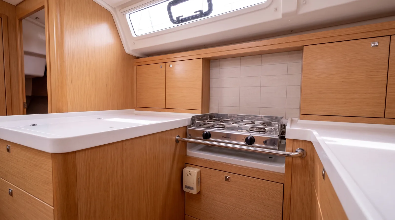 Gasherd mit Schlingerleiste in der hellen Pantry einer Segelyacht, darunter ein Gaswarner in Bodennähe