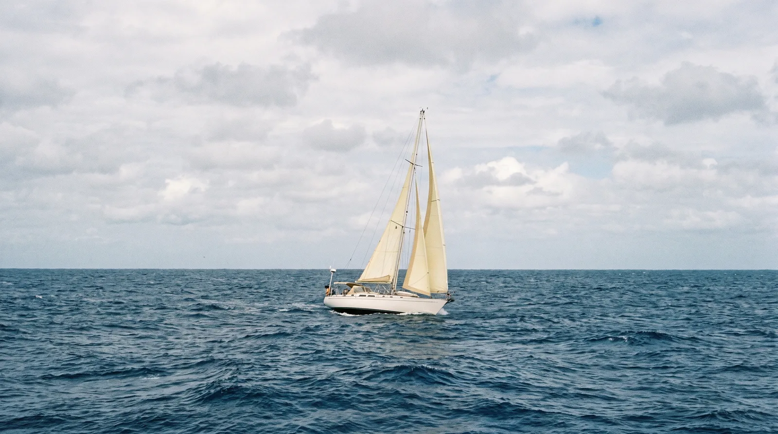 Segelyacht unter Segeln allein auf dem offenen Ozean ohne Küste am Horizont