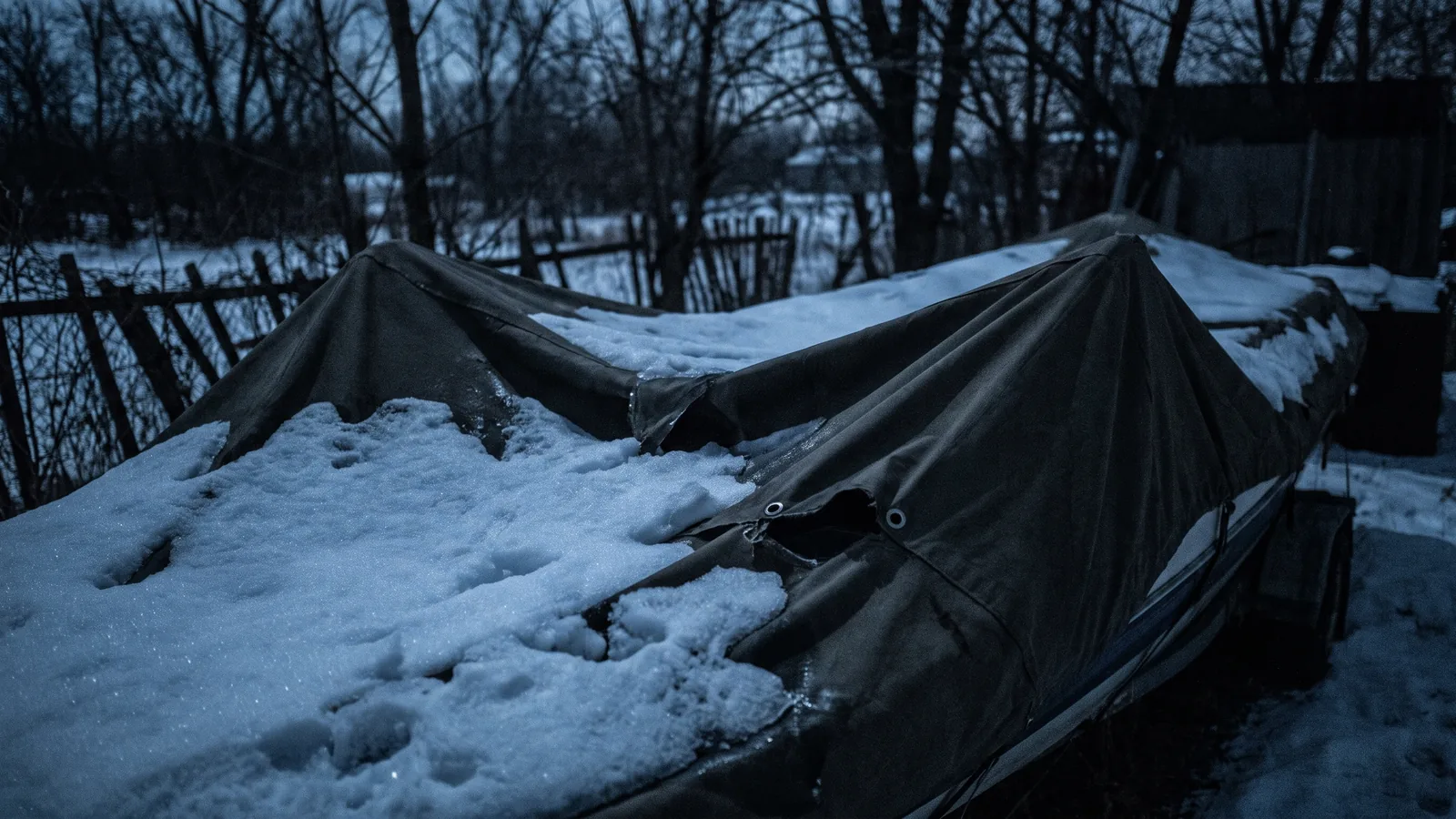 A winter cover sagging under snow over the cockpit of a sailing boat