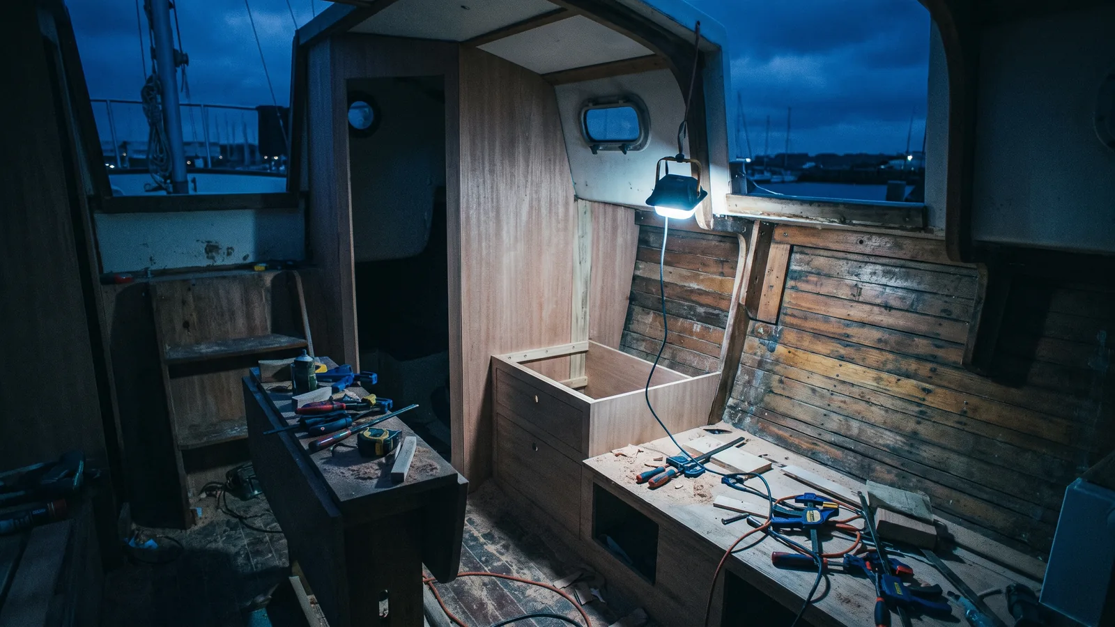A boat interior stripped for a refit at night, new joinery standing next to old